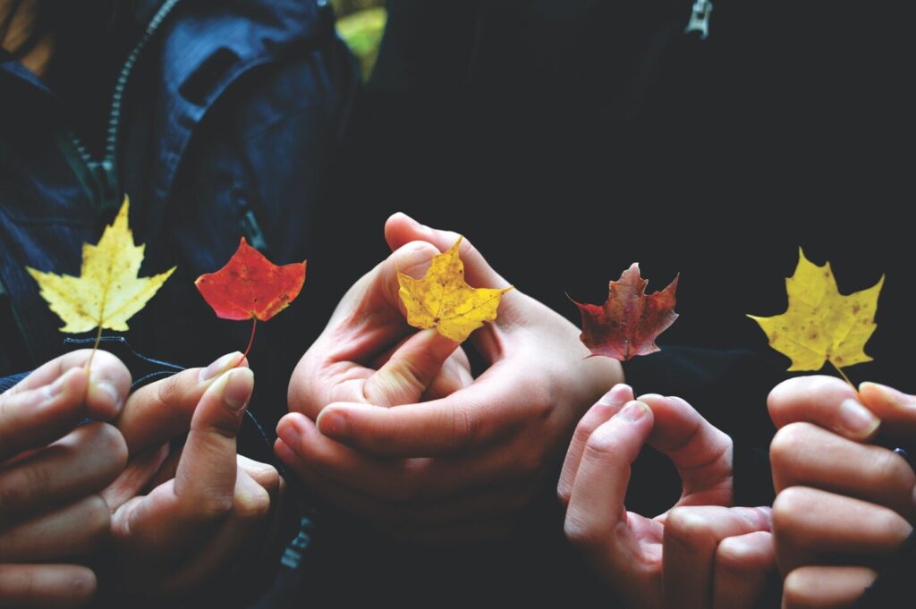 People holding maple leaves - sustainable communities in canada