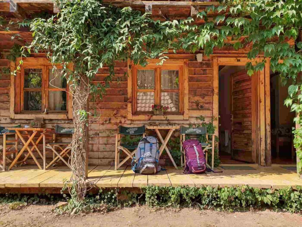 Two backpacks by door of wooden cottage - how building sustainably impacts human health