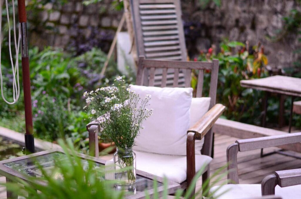 Wooden patio chair and table with flowers - how to create a sustainable outdoor living area