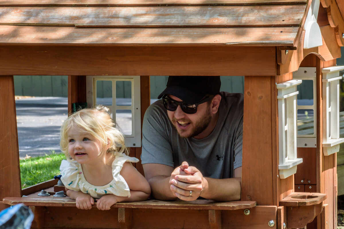 Daughter and father in kids outdoor playhouse